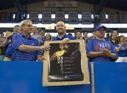 Bruce Bundy, Lawrence, left, and Brian McGee, Gardner, hold up a poster of Olympic gold medalist and Kansas University women's track team member Diamond Dixon as a small crowd gathered inside Allen Fieldhouse on Sunday to welcome home the women's track team.