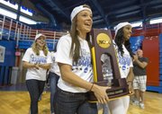Members of the Kansas University women's track carry the national championship trophy into Allen Fieldhouse in front of a small crowd gathered inside on Sunday to welcome the team home.