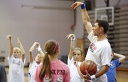 Former Kansas guard Tyrel Reed shows a group of campers some proper shooting techniques on Monday, June 24, 2013 during the Cole Aldrich basketball camp at Olathe Northwest High School.