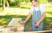 Busby sets a loaf of hot loaf of bread down on a table near his outdoor oven. Busby,
22, sells his bread at a couple of outlets in Baldwin City, and is planning to
expand to the Cottin's Hardware Farmers' Market in Lawrence.