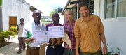 Two villagers, Golden and Selvester, stand with Peace Corps volunteers Samatha Claypool-Temple and Luke Temple after completing a training in Bagamoyo, Tanzania.