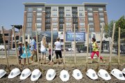 Visitors to the groundbreaking ceremony for the 900 New Hampshire building study a rendering of the structure behind a row of shovels and helmets on July 12, 2013. Many Lawrence residents and business owners attended the groundbreaking for the building, which will become a Marriott hotel and is being built by Lawrence developer Doug Compton, who's company, First Management, also built the loft apartments pictured on the west side of New Hampshire Street. Nick Krug/Journal-World Photo