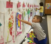 Pre-school student Cole FitzGerald puts up his most recent work or art on the wall in his Lawrence Arts Center classroom Thursday, Sept. 12, 2013. The Arts Center&squot;s "STEAM"-based curriculum overlaps areas of science, technology, engineering, arts and math for students.