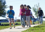 From left, Bennett Stammeyer, 6, Nevaeh Hogan, 6, and Natalie Caroll, 6, are part of the 300-student-strong marathon club at Langston Hughes Elementary School in Lawrence. As part of the physical fitness program, students walk or run at Fred DeVictor Park twice a week. LiveWell Lawrence, which celebrates its fifth anniversary this month, helped spread the program to other elementary schools in Lawrence.