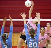 Lawrence High's Caroline Dykes (13) tries to make a kill between Shawnee Mission East blockers Katherine Stiegemeyer (20) and Savannah Bellem (3) during their volleyball match Thursday at LHS.