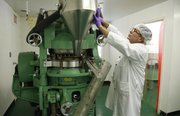 Bill Gaus, a production supervisor at Pines International, tinkers with a tablet making machine as he demonstrates its capabilities for pressing dehydrated wheat grass into tablet form during a tour of the facility on Wednesday, Oct. 23, 2013. The company, which began in 1976, has grown into an international supplier of cereal grass supplements.