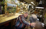 Artist and diorama creator Randall Bennett studies a clay bust while sculpting it in his studio on Oct. 31, 2013. Around him are a wall of his paintings and various leftover elements from dioramas past, such as the corn stalks, purple prairie coneflowers, black-eyed susans and soy-bean plants on the table behind him.