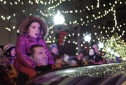 A father and his daughter watch as Santa is rescued from the top of Weaver's Department Store by the Lawrence-Douglas County Fire Medical Department Friday, Nov. 29, 2013. The city also turned on the downtown Christmas lights during the annual event.