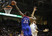 Kansas center Joel Embiid turns for a shot against Colorado forward Dustin Thomas during the first half on Saturday, Dec. 7, 2013 at the Coors Events Center in Boulder, Colorado.
