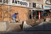 Workmen board up the front of the Strong's Antiques, 1025 Massachusetts St., Saturday morning after a car hit a city planter shortly after 3 a.m., ejecting a 37-year old male driver. A 22-year-old female passenger was also injured. Both were taken to University of Kansas Medical Center in Kansas City, Kan.