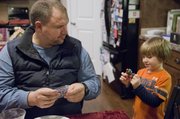 Jason Thornton helps unwrap a toy for his son, Hayden, on Monday, Dec. 16, 2013. Jason's wife and Hayden's mom, Jennifer Thornton, is working on her masters in social work at KU. Jason, retired medically from the Army, suffers from PTSD and chronic depression.