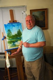 John Parkinson shows off the first painting he completed after two friends and fellow residents at Hancuff Place in Baldwin City gave him an easel. It is the first painting he has done since a stroke following quadruple bypass surgery eight years ago left him legally blind.
