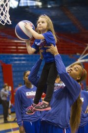 Kansas freshman Caelynn Manning-Allen lifts Avery True, 5, of Topeka, for a basket during the KU women’s basketball holiday clinic, Friday, Dec. 27, 2013, at Allen Fieldhouse.