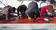 VanGo artists from left, Chris Garrison, Isaiah Young, Jasmine Cable and Drew Sheppard work on painting the "love" garage on Mississippi Street across from Memorial Stadium Sunday afternoon. For many years, the garage was painted red with the word "love" scrolled across it. However, this past June, the garage was painted over blue. The team from VanGo took old photographs of the garage and aim to recreate the old "love" garage while adding in a bit of their own flair.