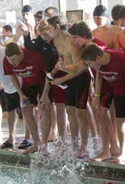 Members of the Lawrence High swim team cheer on the LHS 200-yard medley relay team during the Lawrence Invitational on Thursday at LHS. The Lions' swimming and diving team finished second at their home invitational.