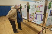 Carl Isenburg and his son Ender 9, a 4th grader at Eudora Elementary School look over some of the Douglas County Science Fair projects at West Middle School on Saturday Feb. 8.