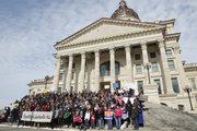 Demonstrators gather on the south steps of the Kansas Statehouse for a group photo by organizers in protest to House bill 2453, a measure approved by the House that would have allowed people to cite religious beliefs in denying services to same-sex couples. The demonstration, which drew several hundred members was organized by the Topeka non-profit group Planting Peace.