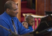 One-year-old Jayvion Lewis, center watches as his grandfather, George Rennels, plays the piano during a worship service at St. Luke AME church, 900 New York St. on Sunday, Feb. 16, 2014. Also pictured is 3-year-old Jeremiah Lewis.