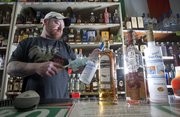 Brian Fadden, owner of Parkway Wind and Spirits at 3514 Clinton Parkway dusts off some bottles on Monday February 24, 2014, preparing them for the shelves.