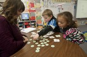 Kennedy Elementary School kindergarten teacher Lauren Mitchell helps Cody Rosebaugh and Brooklynn Clark look for words with certain sounding letters. The exercise was one stop in a reading rotation during the morning portion of Mitchell's full-day kindergarten class.