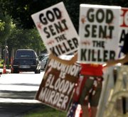 In this June 6, 2009 file photo, protesters from Rev. Fred Phelps' Westboro Baptist Church demonstrate during funeral services for Dr. George Tiller at College Hill United Methodist Church in Wichita, Kan. In an 8-1 ruling, the U.S. Supreme Court ruled the group's protests were protected by the First Amendment. The father of a Marine killed in Iraq sued after they picketed his son's 2006 funeral service.