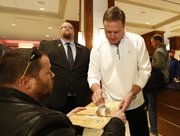 Kansas head coach Bill Self stops to autograph a piece of floor for Don Lienemann, St. Louis, after talking with media members following the team's arrival at the Hyatt Regency hotel at the Arch, Wednesday, March 19, 2014, in St. Louis. The Jayhawks play their first game of the NCAA Tournament on Friday.