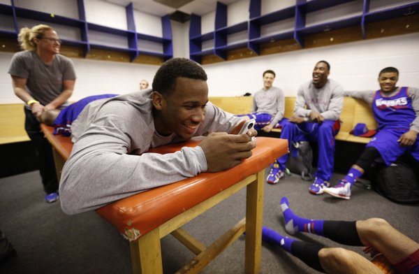 Kansas guard Wayne Selden smiles while thumbing through an iPhone as strength and conditioning coach Andrea Hudy works on this calves in the team locker room during a day of press conferences and practices at the Scottrade Center in St. Louis on Thursday, March 20, 2014.