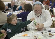 Mike Yoder/Journal-World Photo.Jakob Rudnick, left, with the help of Steve Hurst, Perry, dips a sprig of parsley in a glass of salt water during the the Passover Seder Tuesday, April 15, 2014, at Lawrence Jewish Community Congregation. The Seder ritual included telling the story of liberation of the Israelites from slavery, discussing the story, eating matza, partaking of symbolic foods placed on the Passover Seder Plate, and the celebration of freedom.