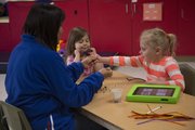 From left, Sandy Davalos Wainwright, an early childhood special education teacher, makes crafts with Isabella Estrada, 4, and Laine Durler, 5, on a recent day at Educare Preschool, 1000 Sunnyside Ave. Laine, who has autism, uses an iPad to communicate as part of a Kansas University research project.