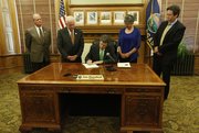 Governor Sam Brownback signs a school finance bill that will increase funding to schools and also contains some controversial policy change, Monday, April 21, 2014 in his ceremonial office at the Kansas Statehouse in Topeka, Kan. With Brownback are Gene Suellentrop, R-Wichita, chairman of the House Appropriations Committee, House Speaker Ray Merrick, R-Stillwell, Senate President Susan Wagle, R-Wichita, and state board of education member Steve Roberts, R-Overland Park.