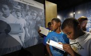 Mecca Cameron, a fifth-grader at McEachron Elementary School in Topeka, examines a historic photo showing Elizabeth Eckford, far left, attempting to enter a high school in Little Rock, Ark., on Sept. 4, 1957. Mecca and Kamarion Smith, right, and other students toured the Brown v. Board of Education National Historic Site on Monday in Topeka.