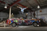 Jeremy Rockwell, Lawrence mixed media artist and avid rollerblader, does a "full torque" trick as he slides over a handrail attached to his "Skate Car," a 1987 BMW 325i, at SeedCo Studios, 826 Pennsylvania. Rockwell plans to drive the vehicle, which is bookended by detachable ramps on both ends, in the Art Tougeau Parade this Saturday.