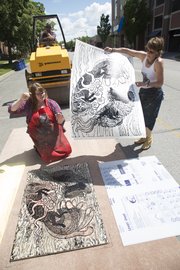 Richard Gwin/Journal World Photo.From left, Dana Rudolph, St. Joe Mo. helps Sally Piller, remove her print as artist's gathered at the Lawrence Arts Center at 940 New Hampshire to watch a city 8,500 lb. roller driven by Andy Breedlove of the Public Works Department pass over blocks of wood artists carved various ides into, creating block prints on Friday May 30, 2014.