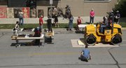 Artists gathered at the Lawrence Arts Center, 940 New Hampshire St., to watch a 8,500-pound roller pass over blocks of wood the artists carved to create prints Friday.