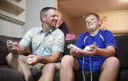 Brandon Urban and his 13-year-old son, Ben, joke with each other while playing a game of FIFA soccer on Nintendo Wii at their Lawrence home on a recent day. Ben was recently diagnosed with Klinefelter's syndrome, a rare disease that gives males an extra X chromosome. Brandon has been participating in charity events to raise money and awareness about the disorder.