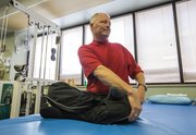 Rick McNabb, of Lawrence, stretches before beginning his routine of climbing steps at Lawrence Memorial Hospital. Four years ago, McNabb suffered an aneurysm which led to a stroke that left him paralyzed and without sensation on the left side of his body. McNabb is attempting to climb the equivalent of Mount Everest while raising money for charity. 