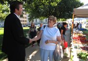 In this photo from Wednesday, Aug. 13, 2014, Chad Taylor, left, Democratic candidate for the U.S. Senate in Kansas, greets Laura Schafer, a retired state employee, at a farmers market on the Statehouse grounds in Topeka. Taylor is the Shawnee County district attorney and hopes unseat veteran Republican Sen. Pat Roberts.