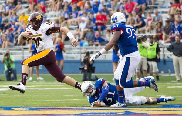 Central Michigan quarterback Cooper Rush (10) escapes from Kansas' Ben Heeney (31) and Ben Goodman (93), scrambling for a first down during their game on Saturday afternoon at Memorial Stadium.
