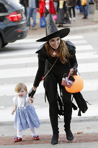 In this file photo, Jordan Noller assists her 13-month-old daughter Scotlyn across the street during the 2013 Downtown Lawrence Halloween Trick-or-Treat. 