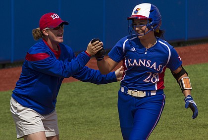 Chanin Naudin gets a high five from Kansas coach Megan Smith as she rounds third base after hitting a second inning solo home run during a game against Texas at Arrocha Ballpark on March 29, 2015.