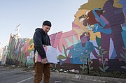 Lawrence artist Dave Loewenstein holds a piece of his Pollinators mural after construction workers began to dismantle the artwork at 9th and New Hampshire on Friday, March 6, 2015.