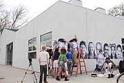 Youths at Van Go Mobile Arts, 715 New Jersey St., install photos for Lawrence Inside Out project on the exterior of the building during a workshop Friday.