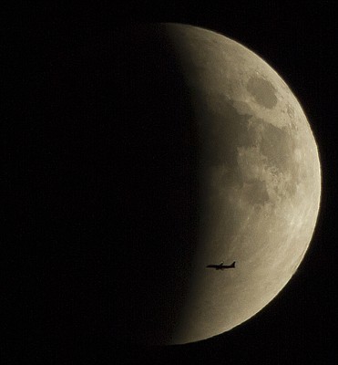 A plane is framed against the eclipsing moon Sunday night, Sept. 27, 2015. A harvest moon and the blood moon eclipse has led many to call this event a rare super blood moon. This combination of events won't happen again until 2033. 