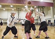 Michele Clark, of Lawrence, center, catches a pass under the basket as Mary Pat Pellett, left, of Lawrence, and Diane Knowles, left, of Topeka, defend during the first game of the Granny Basketball League in Kansas Saturday evening at Holcom Park Recreational Center, 2700 W 27th Street.