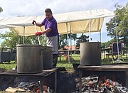 Haskell Indian Nations University cafeteria worker Benjamin Rowland cooks pots of bison chili, bison hominy stew and sweet corn bison stew over an open flame on the Haskell campus Thursday, Sept. 22, 2016. The food was for a bison feast planned in conjunction with a two-day conference on climate change being held at the university.