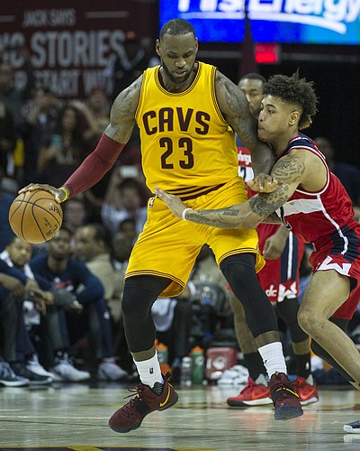 Cleveland Cavaliers' LeBron James (23) keeps the ball from Washington Wizards' Kelly Oubre Jr. (12) during the second half of an NBA basketball game in Cleveland, Saturday, March 25, 2017. (AP Photo/Phil Long)