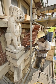 Worker Angelo Epps chisels away some of the mortar below one of the Dyche Hall "grotesques" perched outside the seventh floor as work continues, Wednesday, Aug. 30, 2017 along the exterior of the building on the campus of the University of Kansas. The grotesques, which have suffered significant erosion, have been a part of Dyche Hall for nearly 115 years, according to KU officials.