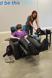 Tashina Case, general manager of Optimal Wellness and Cryospa, adjusts NormaTec settings for Journal-World health reporter Mackenzie Clark.