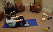 Becky Bridson, a Lawrence-based Yamuna body rolling practitioner, guides Journal-World health reporter Mackenzie Clark through rolling the right side of her back.