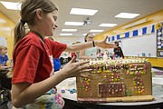Sunflower Elementary fifth-grader Zoey Miller adds sprinkles to a snowman on the roof of a gingerbread likeness of Allen Fieldhouse on Wednesday, Dec. 20, 2017 at the school. Several classes at the school participated in constructing gingerbread representations of Lawrence's iconic buildings and landmarks, which they shared digitally with pen pals in Lithuania.